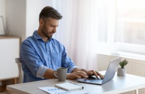 Unemployed man scrolling job search website at home using laptop computer