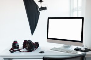 Workplace of photographer with empty computer screen and camera accessories, photostudio with